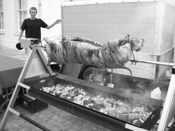 Black and white of Fergus Cadogan with a spit roasted pig